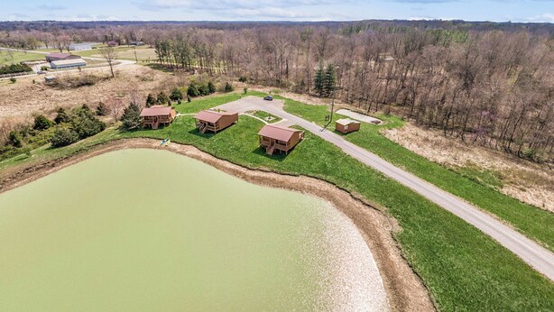 A large outdoor area with a pond, several wooden cabins, and a road. - Pet Friendly! Couples Retreat in Southern Illinois (Murphysboro)