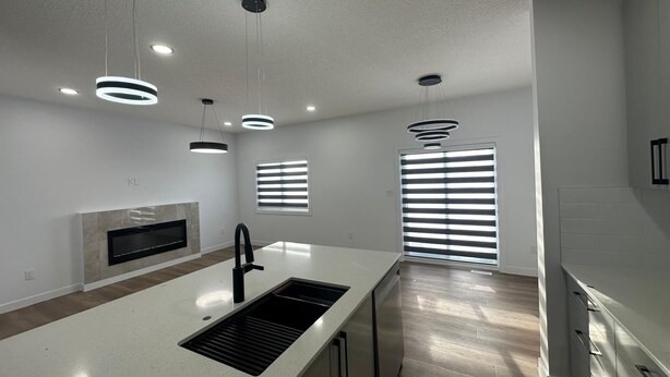 A modern kitchen with a central island, recessed lighting, and a built-in oven. - Luxury Duplex in Spruce Grove (Spruce Grove)