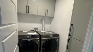 A compact kitchen with two stainless steel washing machines, a built-in sink, and a refrigerator. - Luxury Duplex in Spruce Grove (Spruce Grove)