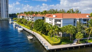 A waterfront hotel with multiple-story buildings, a dock with boats, and a well-maintained garden with palm trees. - Serene Waterfront 2BR  Poolside Living in Fort Lauderdale (Fort Lauderdale)