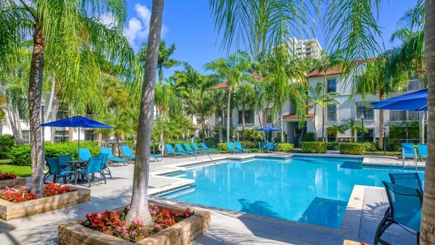 A pool area with lounge chairs and palm trees. - Serene Waterfront 2BR  Poolside Living in Fort Lauderdale (Fort Lauderdale)