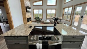 A modern kitchen with granite countertops, stainless steel appliances, and a large window overlooking a scenic landscape. - Spruce Arch | King Bed; Fireplace; Pets Welcome! (Wolfe County)