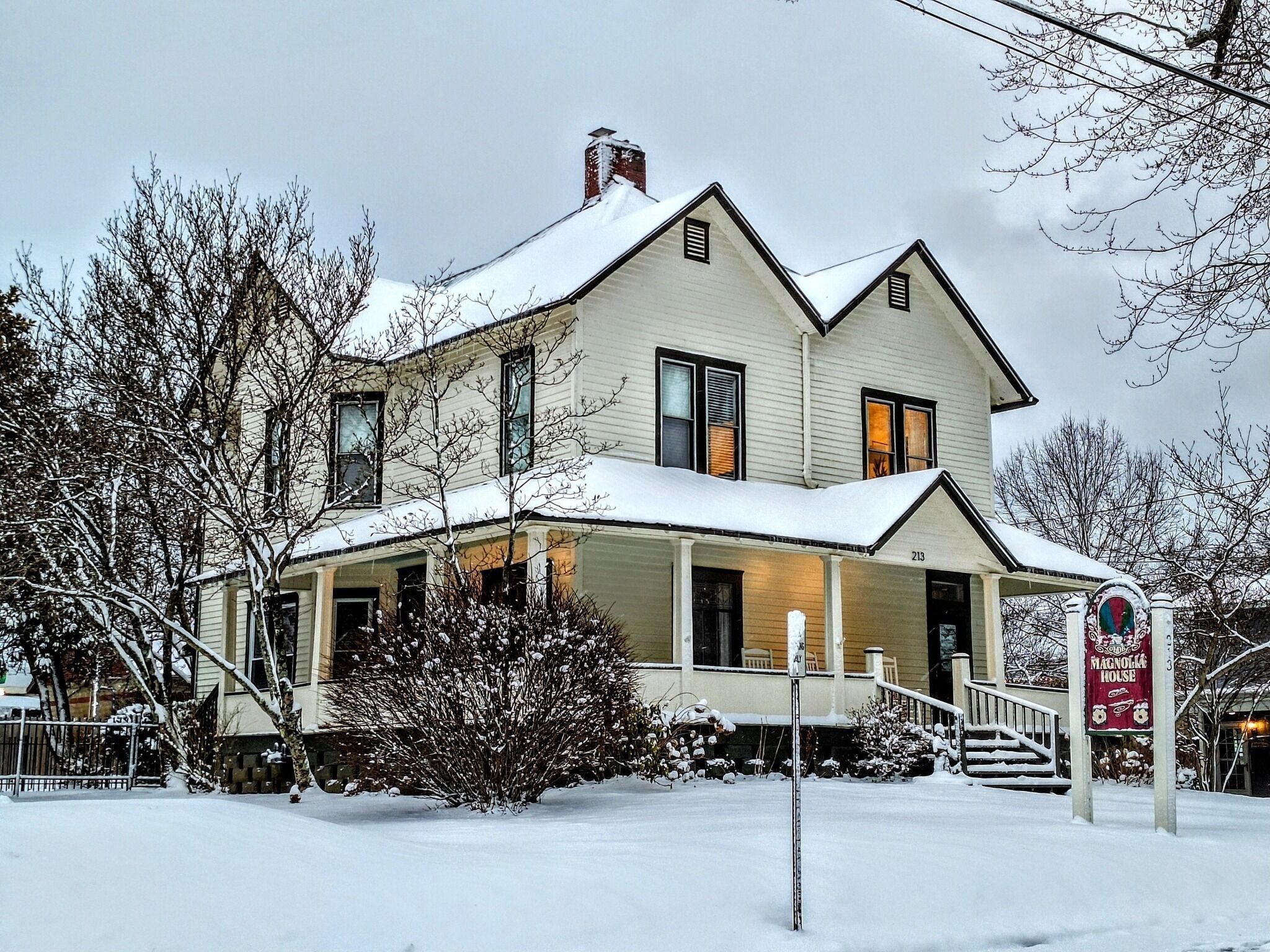Une maison à deux étages, dont le toit est recouvert de neige et qui possède un porche.