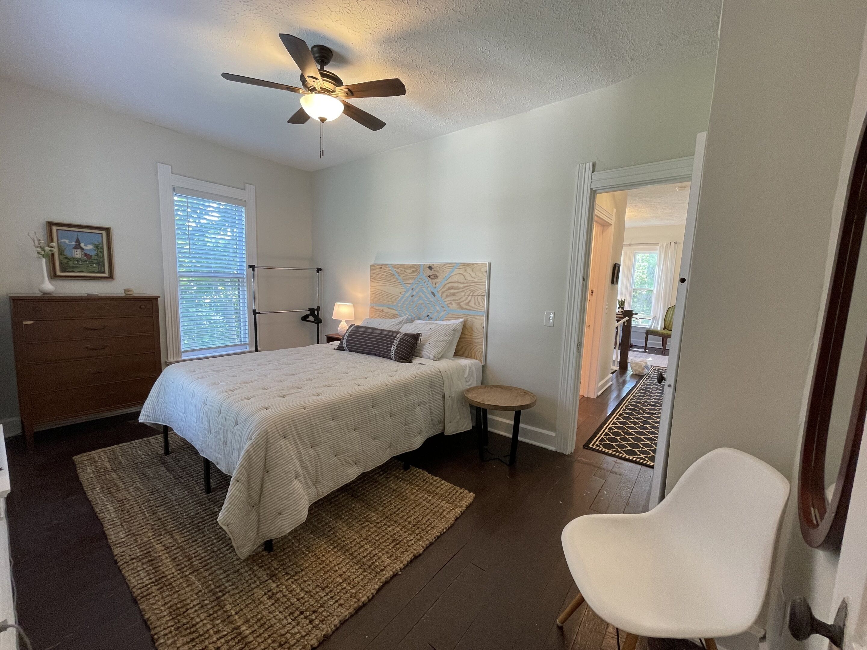 Une chambre à coucher comprenant un lit, des tables de chevet, un ventilateur de plafond, une commode et une chaise.