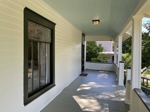 A covered porch with a window and a light fixture.