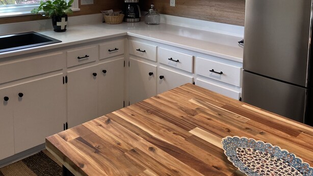 Eine moderne Küche mit weißen Schränken, einem Edelstahlkühlschrank und einer Holz Arbeitsplatte.