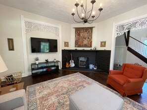 A living room with a fireplace, a television, and a red armchair.