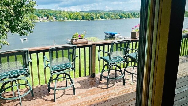 A wooden deck with metal chairs and a table overlooking a lake. - 4 Bedroom Lake House - Northern Michigan (Central Lake)