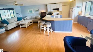 A spacious living area with a sofa, coffee table, and bar stools. A kitchen with a microwave, stove, and refrigerator is visible. - 4 Bedroom Lake House - Northern Michigan (Central Lake)