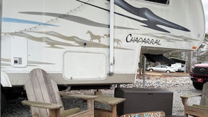 A recreational vehicle (RV) with the name 'Chaparral' on its side, a small wooden table, a bench, and a sign that reads 'LAKE HOUSE'. - Cozy RV in a vacation community on Lake Hartwell (Westminster)