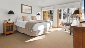 A bedroom with a large bed, two bedside tables, a mirror, and a view of a snowy landscape through large windows. - RMR: Teton Pines 3443 Townhome in Wilson, WY (Wilson)