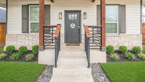 A house with a stone facade, a dark front door, and a welcoming sign. - Family Friendly | Patio | Fireplace | BBQ | Games (San Antonio)