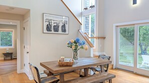 Ein Essbereich mit einem Holztisch, Stühlen, einer Vase mit Blumen und einem gerahmten Bild an der Wand.