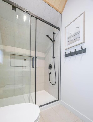 A modern bathroom with a glass-enclosed shower, a white toilet, and a framed picture on the wall. - Sommet Freya - Modern and Family-Friendly with Spa (Saint-Basile)