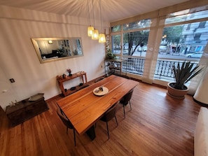 A dining area with a wooden table, chairs, a mirror, pendant lights, and a potted plant. - Fully furnished apartment in Condesa, one of the best neighborhoods in CDMX (Ciudad de México)