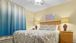 A bedroom with a bed, two bedside tables, a ceiling fan, and a wall-mounted lamp. - ML238 Breathtaking Mountain View Ski in/out at Ballhooter lift, Next to Village! (Snowshoe)