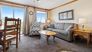 A living room with a wooden dining table, a gray sofa, a patterned armchair, and a ceiling fan. - ML238 Breathtaking Mountain View Ski in/out at Ballhooter lift, Next to Village! (Snowshoe)