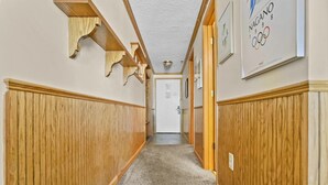 A hallway with wooden paneling on the walls, a carpeted floor, and a door at the end. - ML238 Breathtaking Mountain View Ski in/out at Ballhooter lift, Next to Village! (Snowshoe)