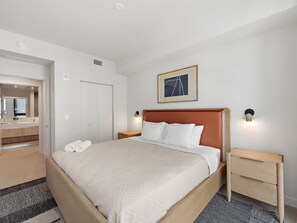 Een hotelkamer met een bed, nachtkastje, spiegel en een lijst aan de muur.