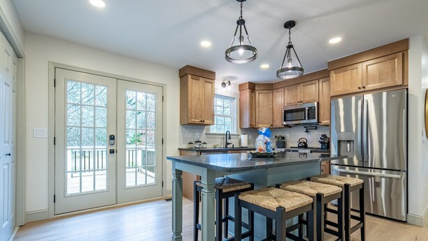 A modern kitchen with wooden cabinets, stainless steel appliances, and a central island with bar stools. - Peaceful Rydal Retreat With Modern Comforts (Rydal)