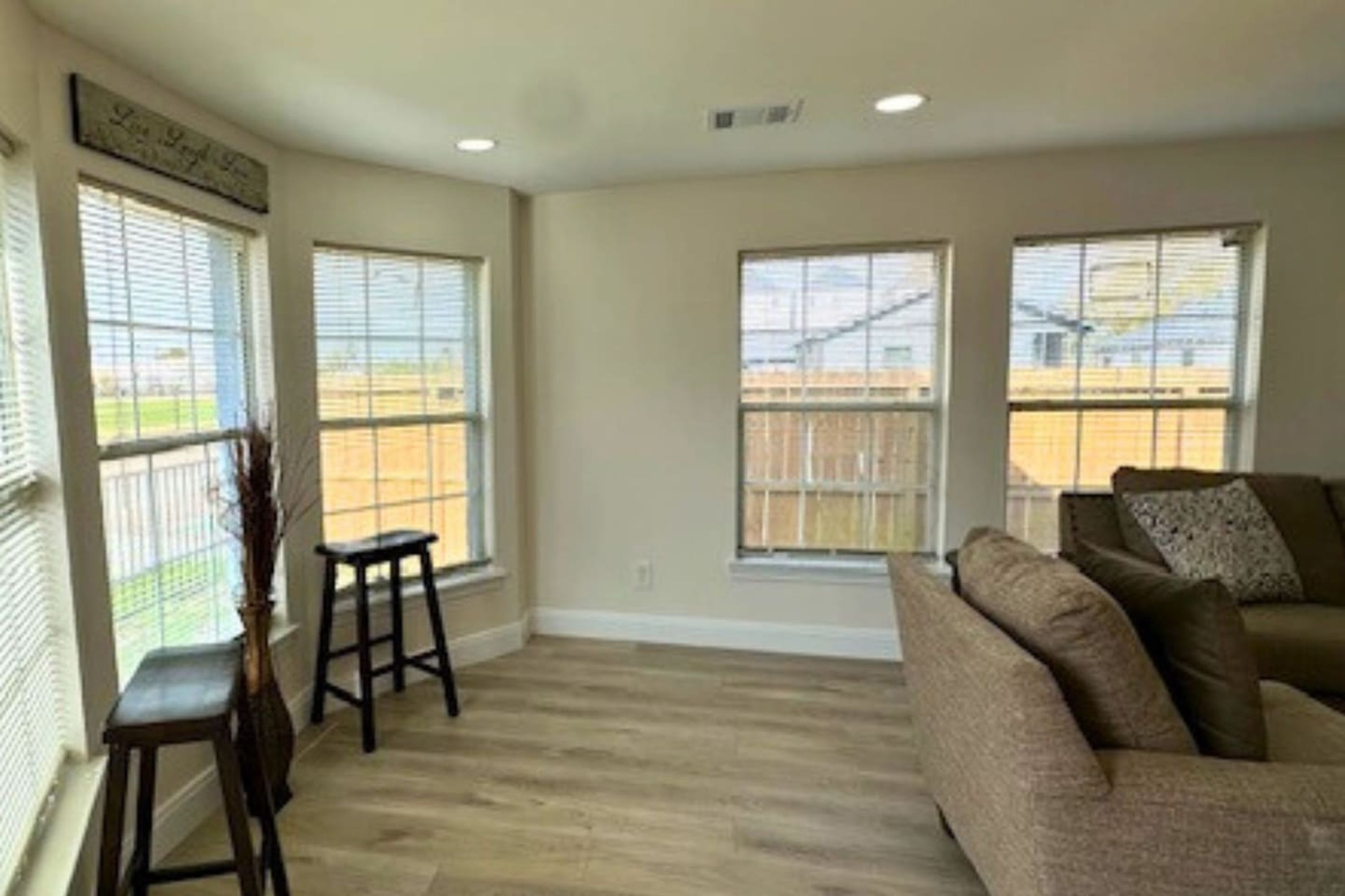 A spacious living room with a large window, a sofa, and two barstools.