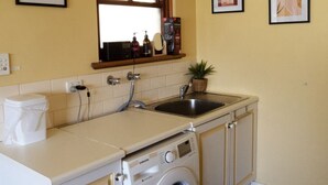 A compact kitchen with a built-in washing machine, a sink, and a window above the counter. - Hilltop Haven Adelaide Hills Retreat Pet Friendly with Night and Day Yards (Mylor)