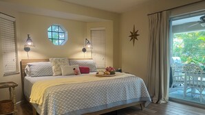 Ein Schlafzimmer mit Bett, Nachttischen, einem Fenster mit Jalousien, einer Sternen-Dekoration und Blick auf eine Terrasse.