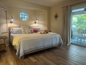 Ein Schlafzimmer mit Bett, Nachttischen, einem Fenster mit Jalousien, einer Sternen-Dekoration und Blick auf eine Terrasse.
