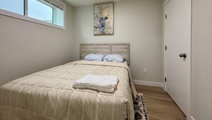 Un dormitorio con cama, ventana, puerta y una obra de arte colgada en la pared.