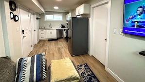 Una cocina compacta con armarios blancos, un refrigerador gris y un horno integrado.