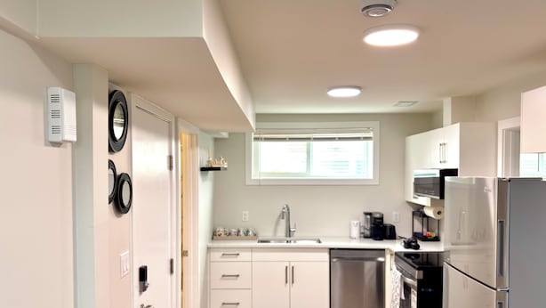 Cocina moderna con armarios blancos, electrodomésticos de acero inoxidable y encimera negra.