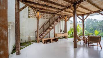 Un espace extérieur abrité, doté d’un escalier en bois, d’un banc et de deux fauteuils en osier.