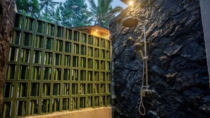 A spa area with a stone wall, a wooden screen, and a shower. - Moonlit Jungle (Tampaksiring)