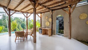 A covered outdoor area with a pool, wooden furniture, and a small kitchen area. - Moonlit Jungle (Tampaksiring)