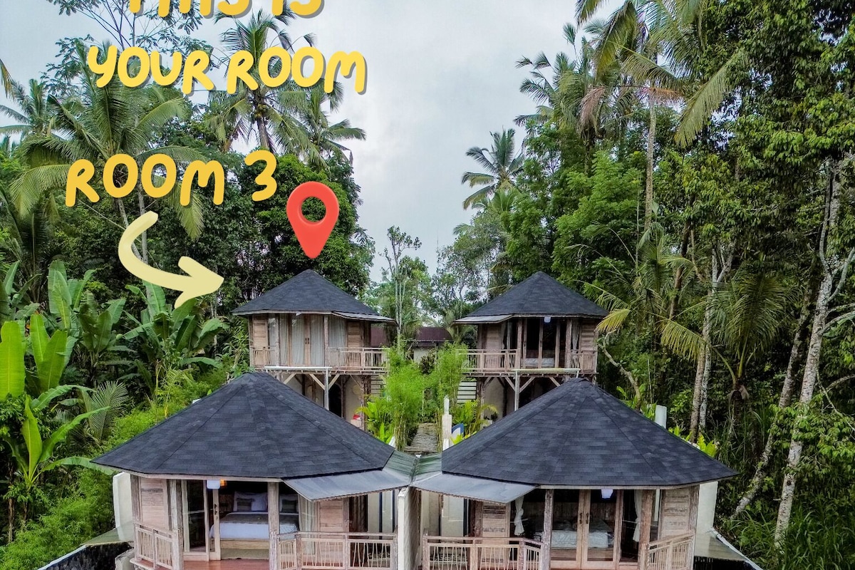 Una casa de madera de dos pisos con balcón, piscina y exuberante vegetación tropical.