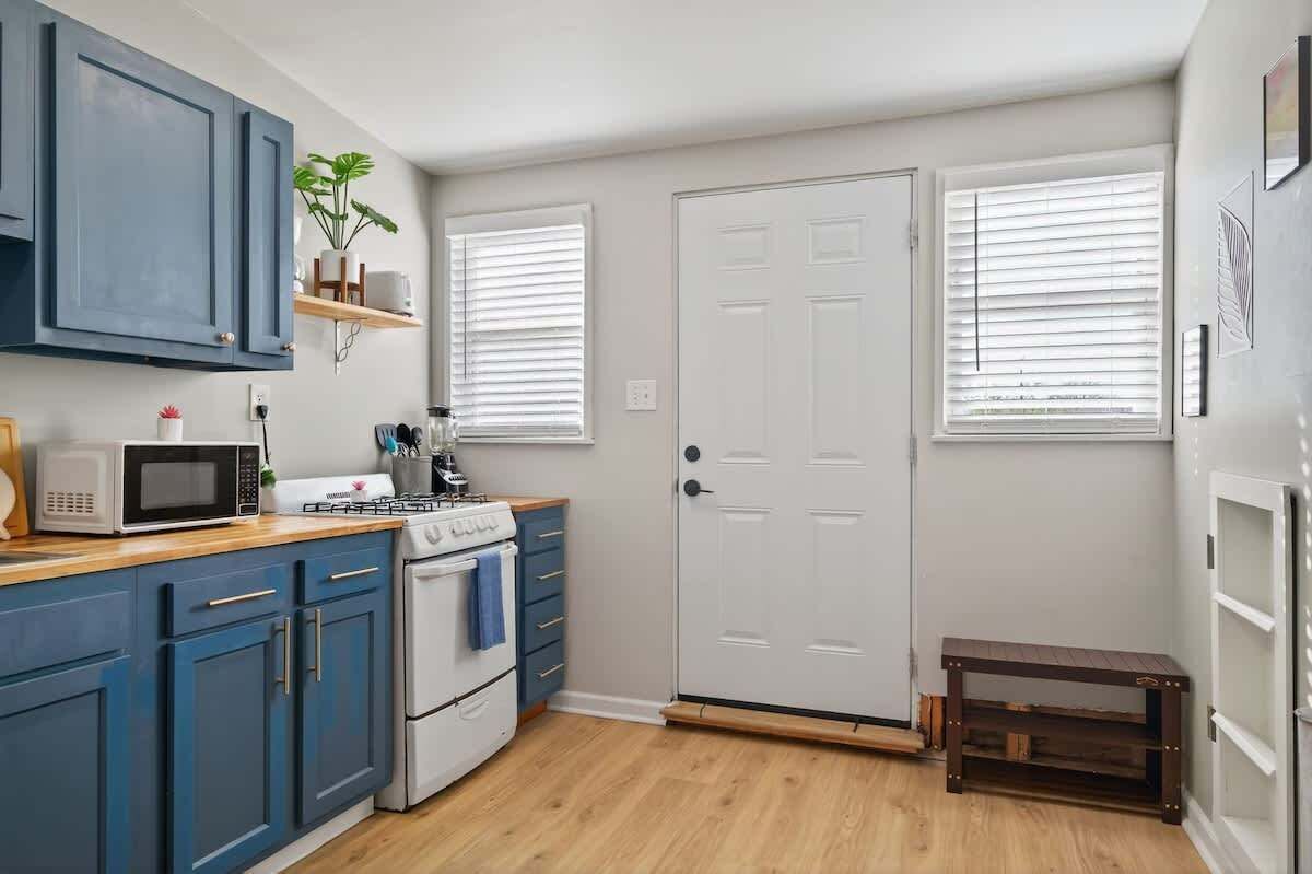 Une cuisine compacte avec des meubles bleus, un four à micro-ondes, une cuisinière et une petite table.