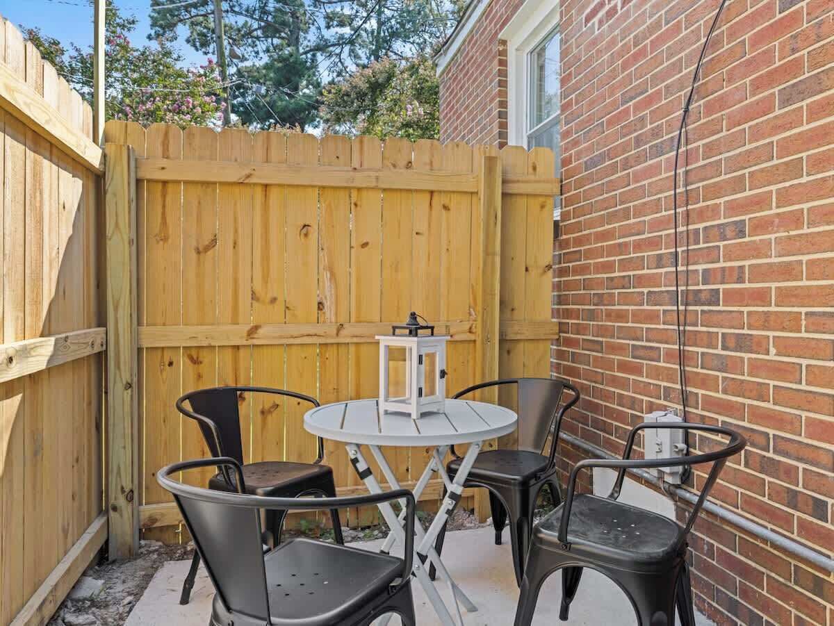 Eine Terrasse mit einem runden Tisch, vier Stühlen, einem Laternenlicht und einer Backsteinmauer.