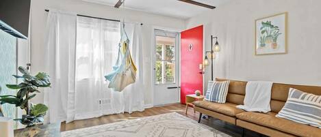 Un salon avec un canapé, un fauteuil suspendu, un tapis et une plante.