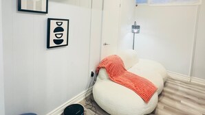Ein Zimmer mit Sitzsack, blauem Stuhl und Staubsauger auf dem Boden.