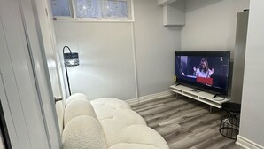 Ein modernes Wohnzimmer mit einem großen Flachbildfernseher, einem weißen Sitzsack und Holzboden.