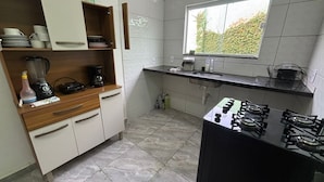 A compact kitchen with a gas stove, a coffee maker, and a blender on the counter. - Beach house in Buzios for up to 8 people. (Armação dos Búzios)