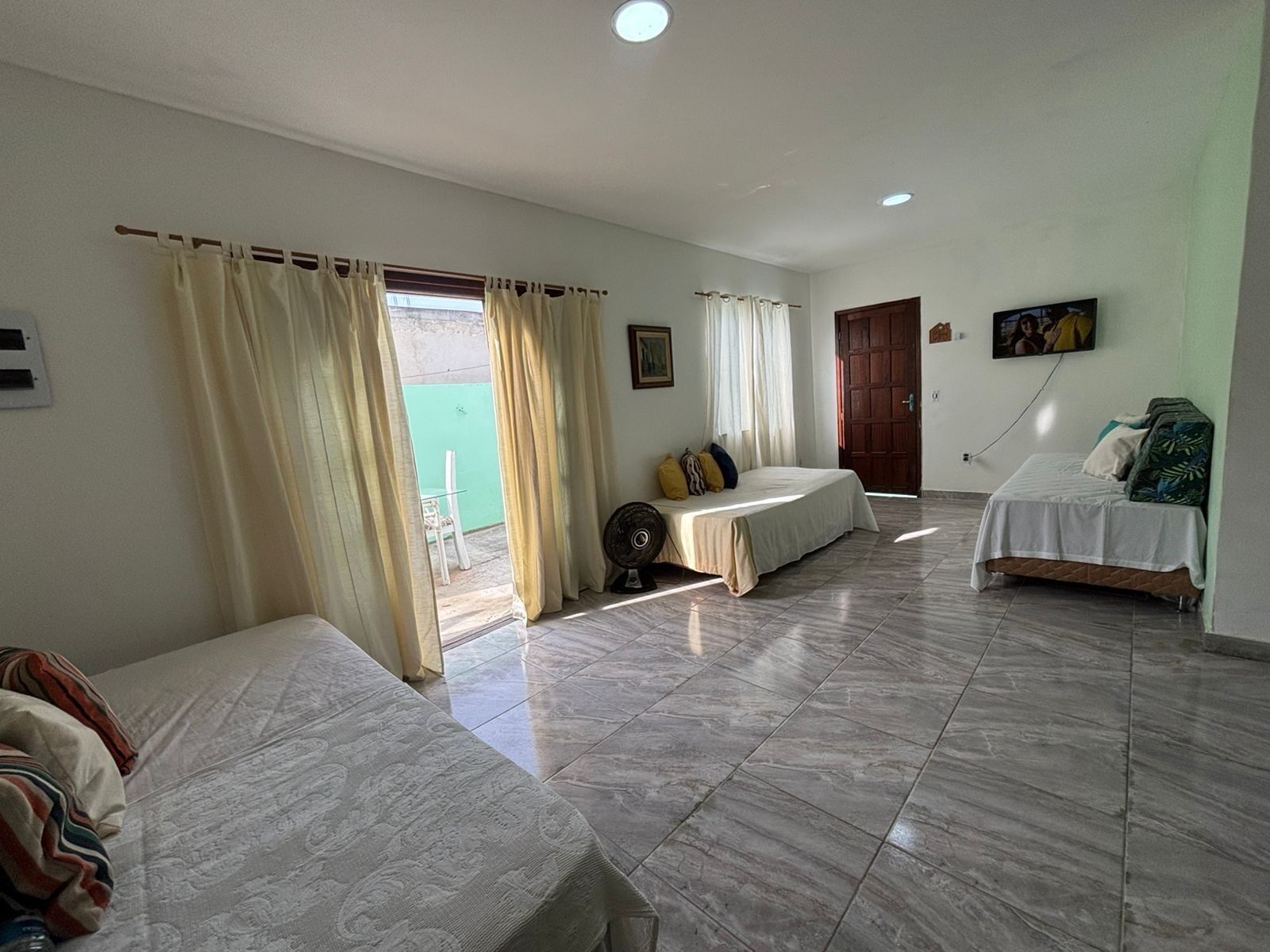 A room with two beds, a fan, and a TV.