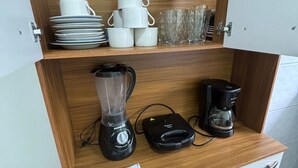 A kitchen area with a wooden countertop, a blender, a coffee maker, and various kitchenware including plates, cups, and glasses. - Beach house in Buzios for up to 8 people. (Armação dos Búzios)