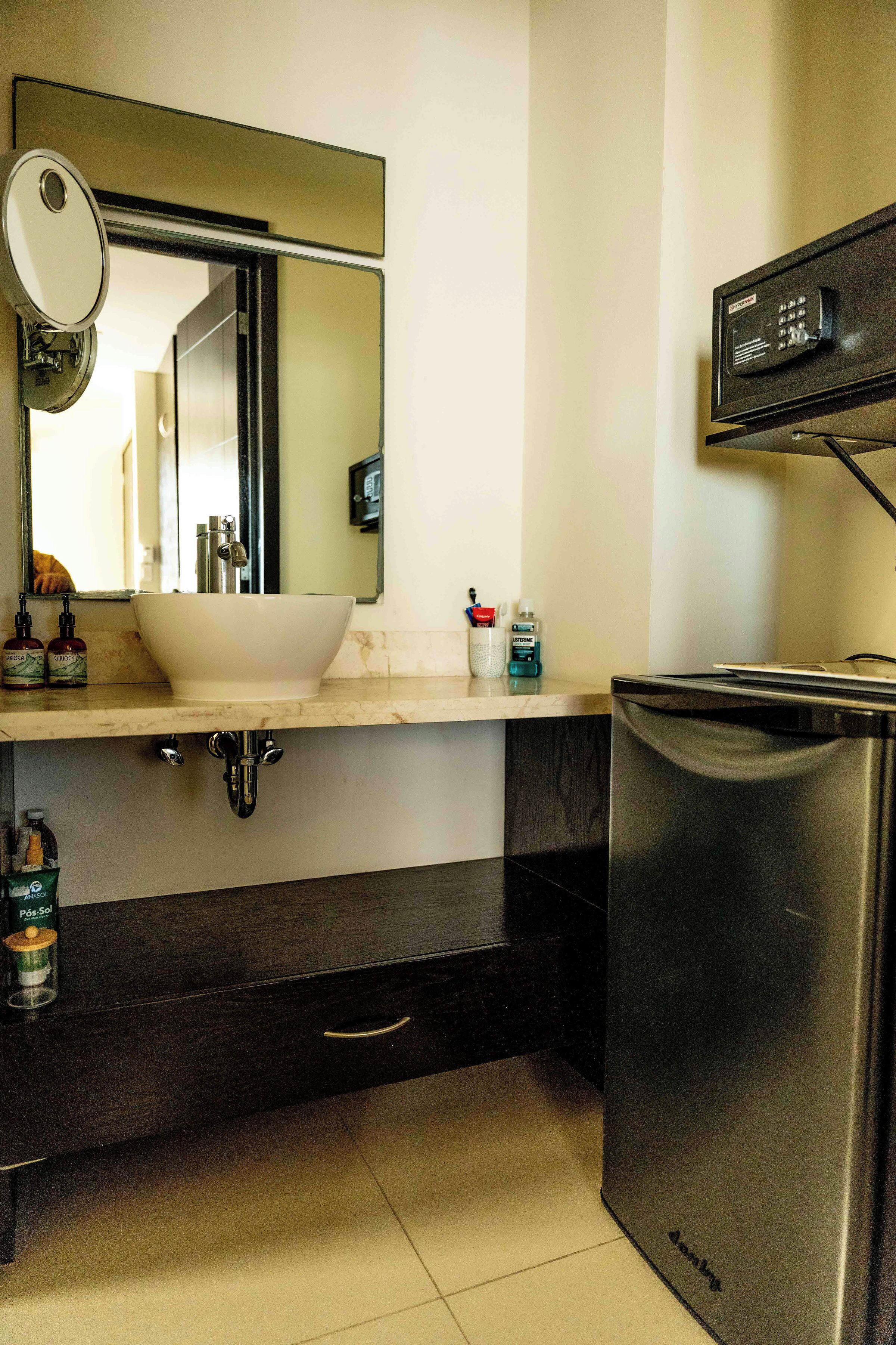 A modern bathroom with a white sink, a large mirror, a black cabinet, and a built-in dishwasher.