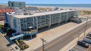 Un hotel de varios pisos con techo plano, estacionamiento y vista a la playa.
