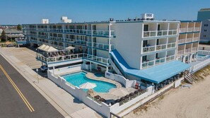 Un hotel de varios pisos con piscina, balcones y ubicación frente a la playa.