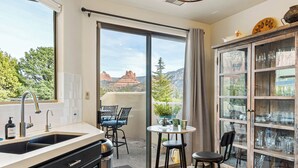 A kitchen with a sink, a dining area with a table and chairs, and a glass cabinet with glassware. - Experience luxury at Sedona Willow Villa—spacious 3BR home with stunning Red Rock views! (Sedona)