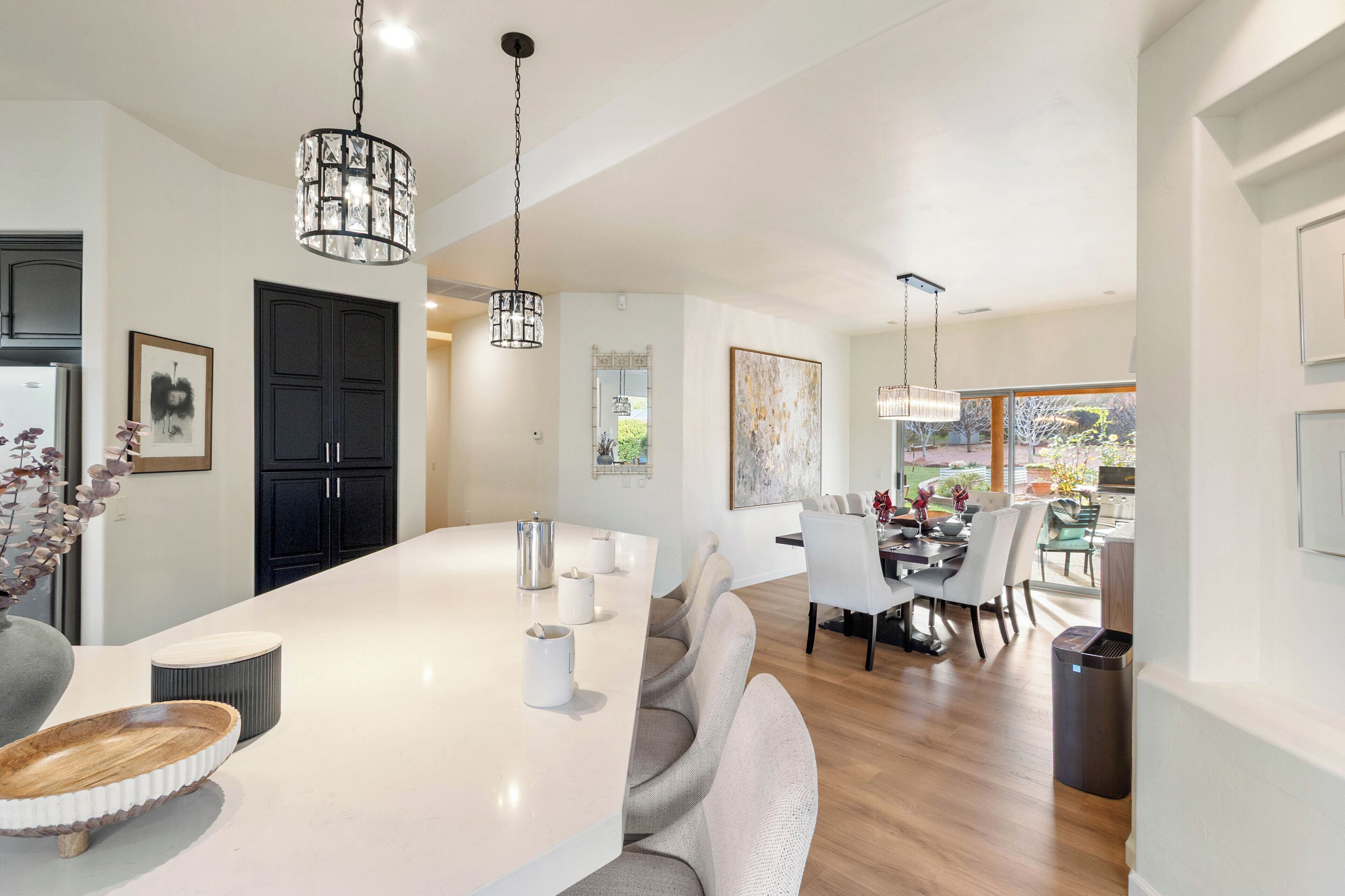 Une cuisine moderne dotée d’un grand îlot central, de luminaires suspendus et d’un coin repas avec des chaises et une table.