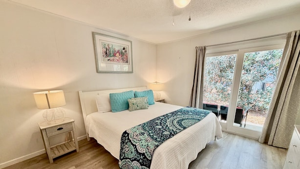 Camera da letto con un letto, comodini, una lampada, un quadro appeso e vista dalla finestra.