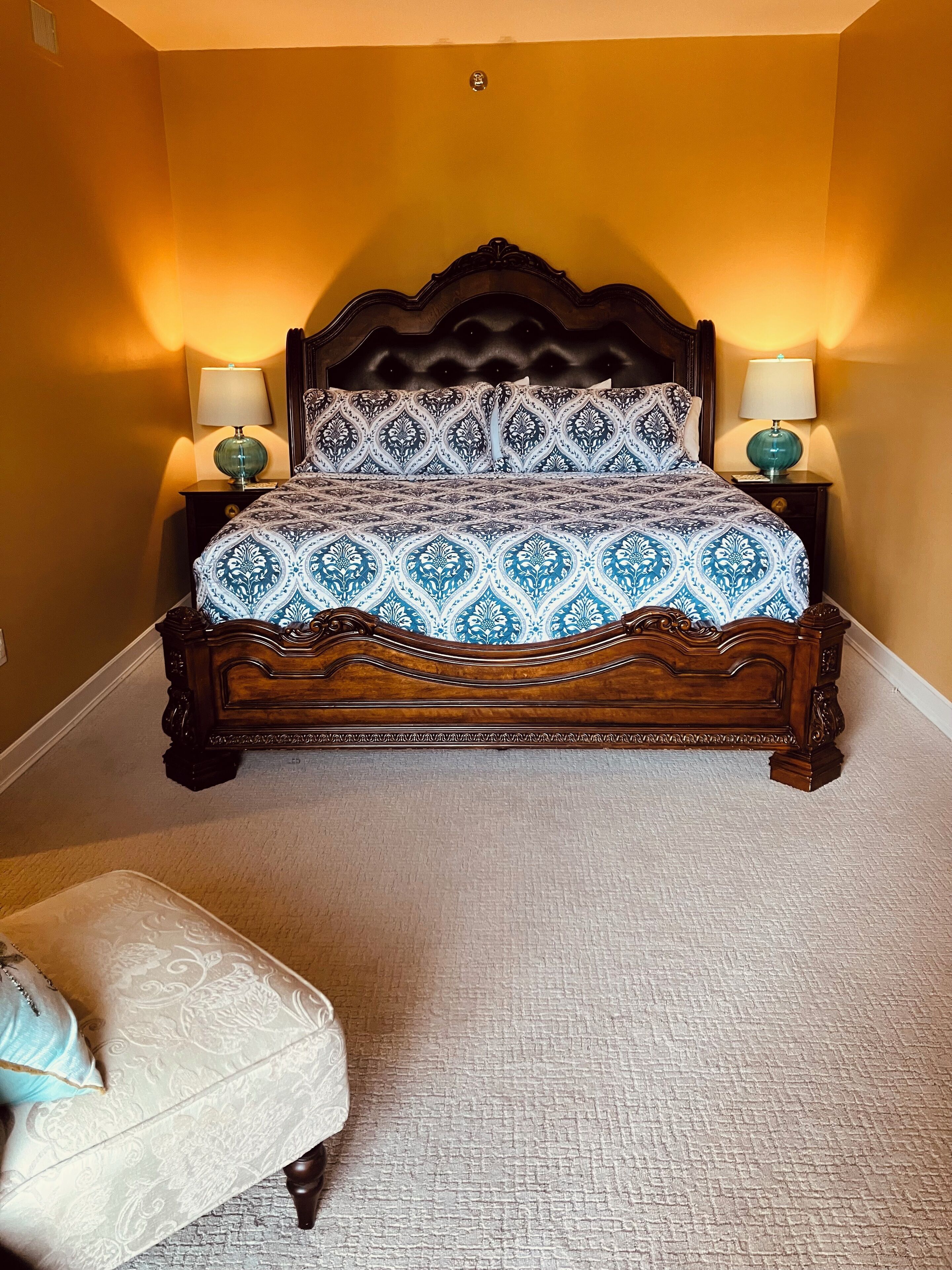 Une chambre à coucher avec un grand lit, deux tables de chevet avec des lampes et une chaise assortie.